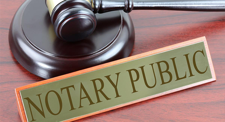 Notary public sign on a desk beside a judge’s gavel, symbolizing legal and notarization services in Ottawa.